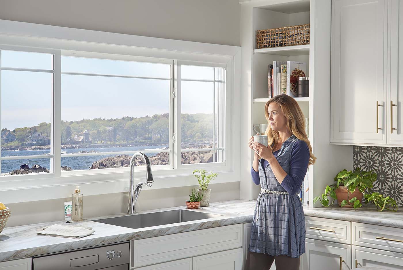 Woman drinking coffee and gazing out through bay window